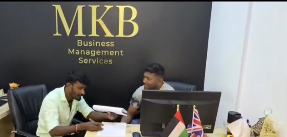 استشارة مع عميل في مكتب استقبال MKB أسفل جدار شعار MKB الذهبي